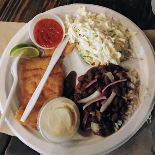 A B.O.'s Fish Wagon seafood platter with fried fish, coleslaw, rice, black beans, and sauces.