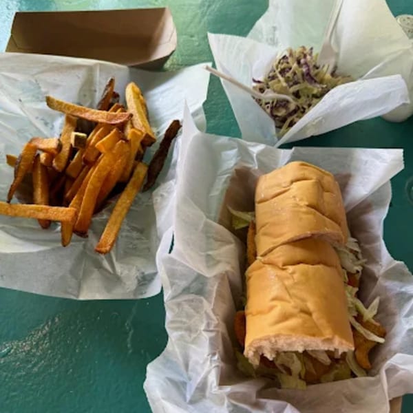 A B.O.'s Fish Wagon fried fish sandwich, fries, and coleslaw in paper-lined baskets.