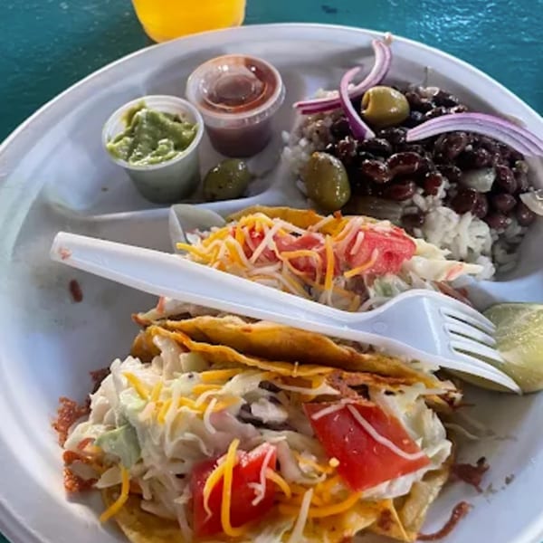A plate of B.O.'s Fish Wagon tacos with rice, black beans, guacamole, and salsa.
